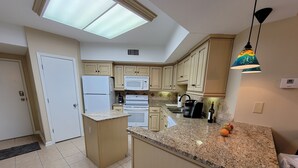 A kitchen with a central island, white appliances, and a skylight. - WATCH THE DOLPHINS PLAY FROM THE BALCONY! (Orange Beach)