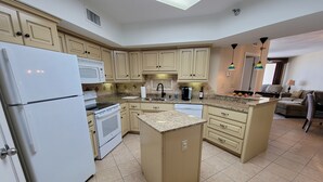 A modern kitchen with beige cabinetry, a white refrigerator, a stove, and a dishwasher. - WATCH THE DOLPHINS PLAY FROM THE BALCONY! (Orange Beach)