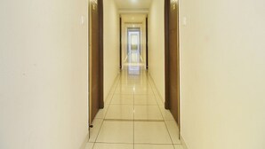 A corridor with wooden doors on either side, leading to a bright room at the end. - Ranas Residency (Tiruchirappalli)