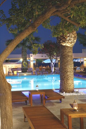A poolside area with wooden loungers, a palm tree, and a pool. - Glaros Beach Hotel (Hersonissos)