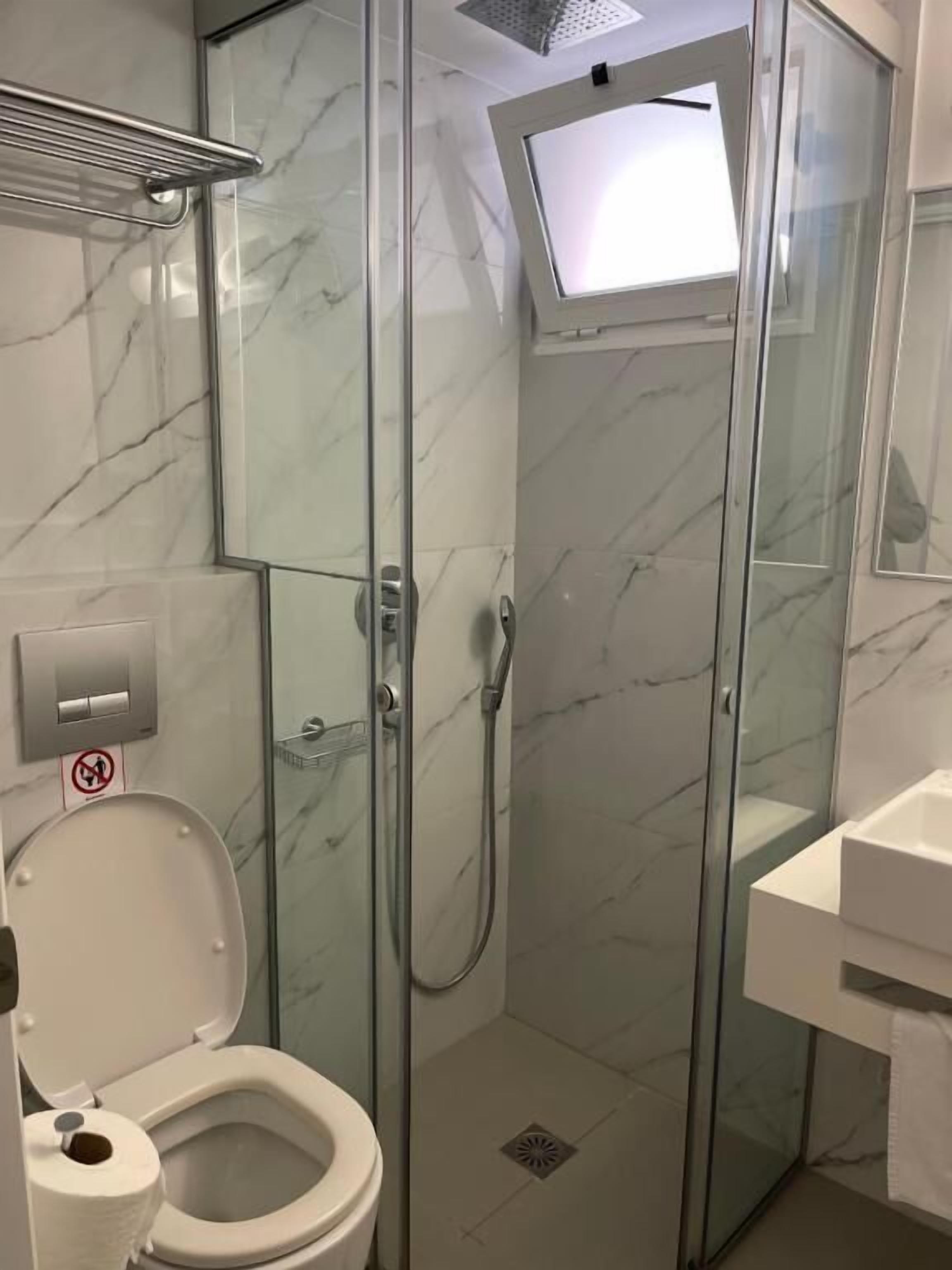 A modern bathroom with a glass-enclosed shower, a toilet, and a sink.