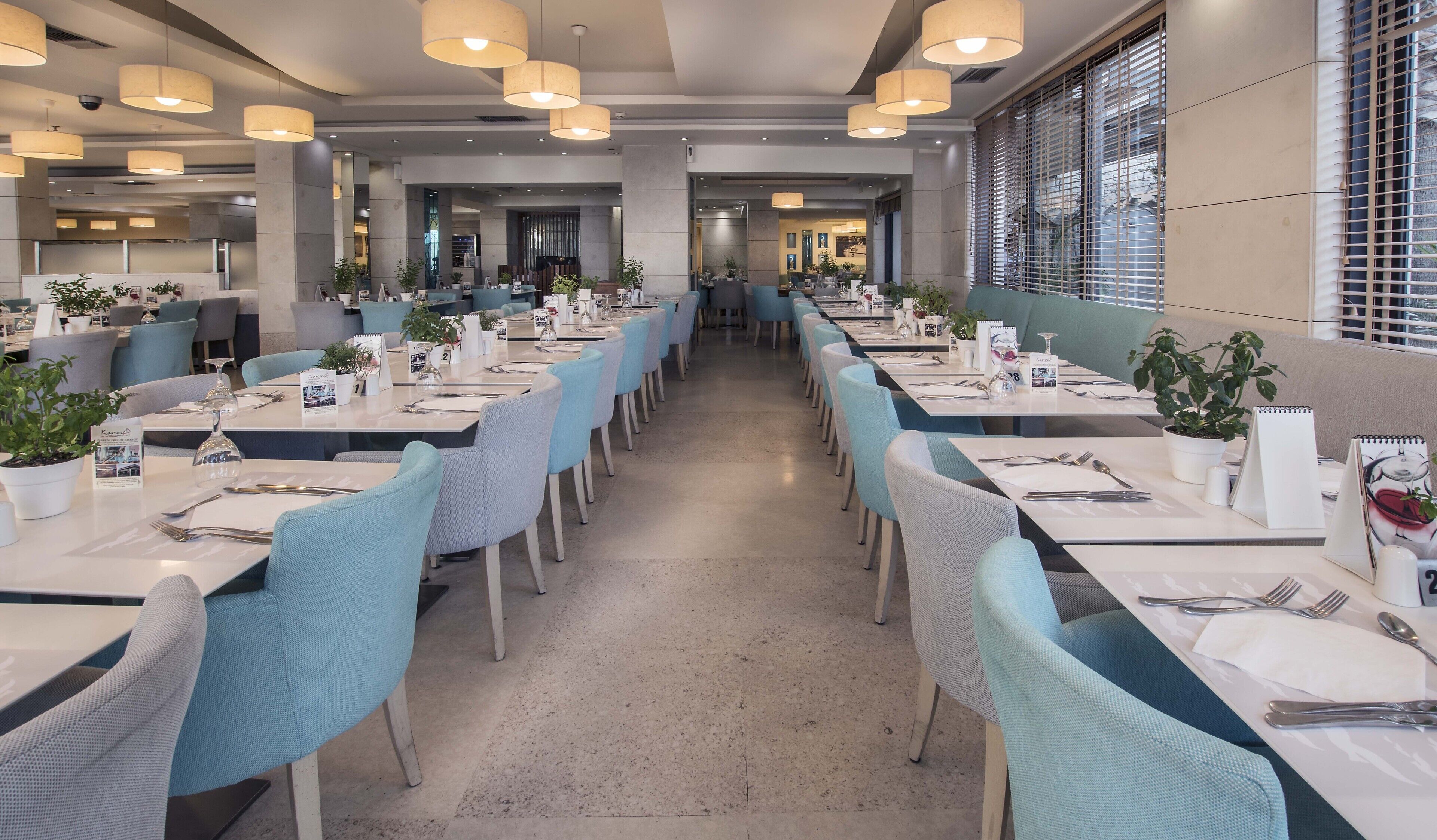 A spacious dining area with multiple tables, chairs, and potted plants.