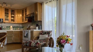 Una cucina moderna con mobili in legno, un'area da pranzo con tavolo in vetro e un angolo relax con tappeto decorato.