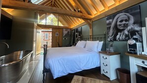 A bedroom with a large bed, a wooden ceiling, a bathtub, and a desk with drawers. - NoTwenty9 Bar and Restaurant  (King's Lynn)