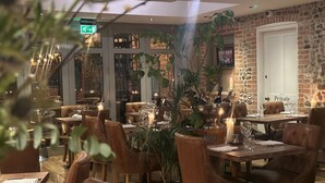 A restaurant interior with leather chairs, tables set with wine glasses, candles, and a large plant centerpiece. - NoTwenty9 Bar and Restaurant  (King's Lynn)