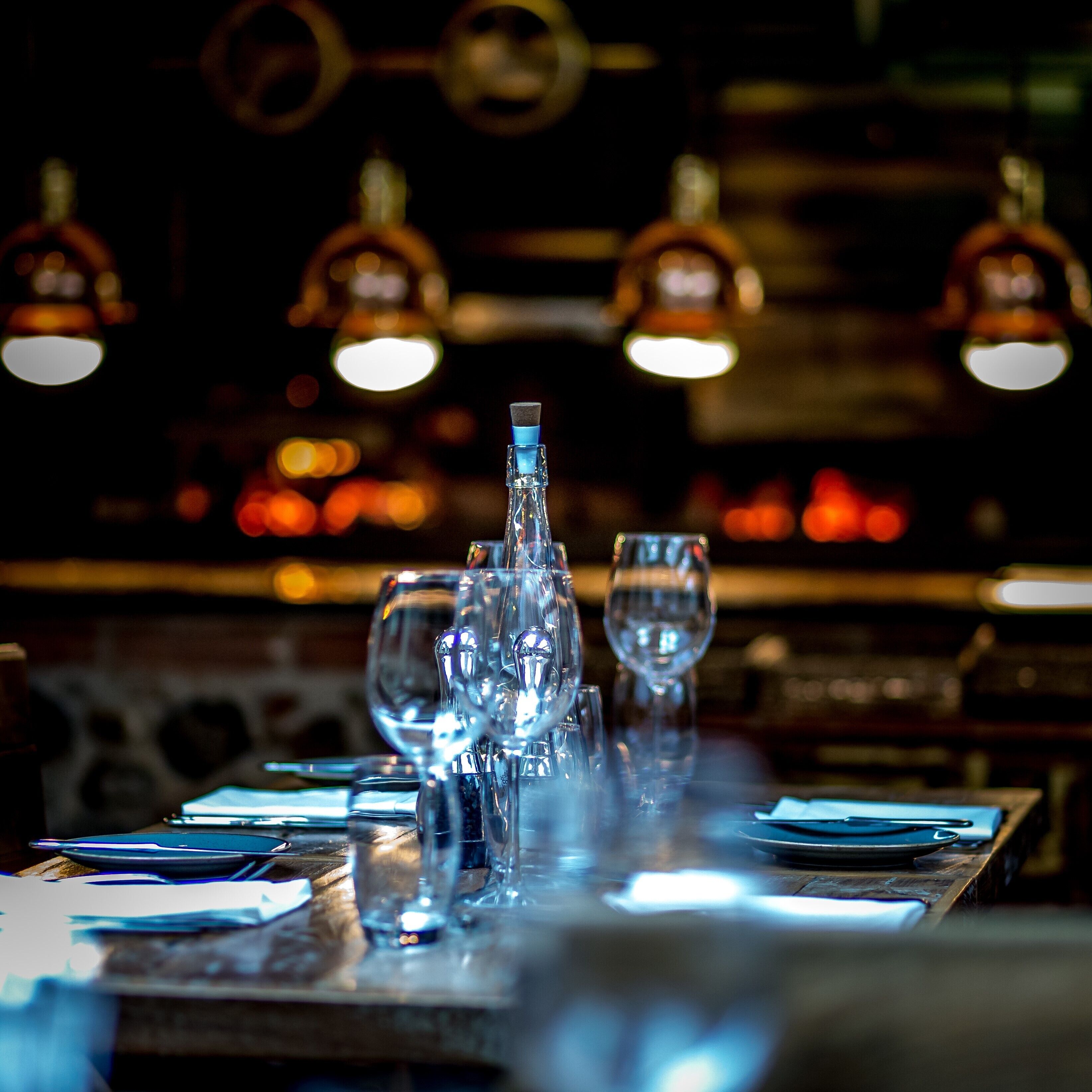 A bar setting with a long table, multiple glasses, and a bottle.