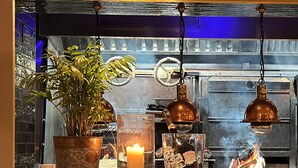 A bar area with a potted plant, a candle, a glass, and a bottle of liquor. - NoTwenty9 Bar and Restaurant  (King's Lynn)