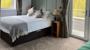 Una camera da letto con un letto, un comodino, un divano verde e una porta scorrevole in vetro che dà su un balcone.