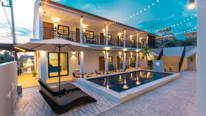 Un hotel con piscina, asientos exteriores y una estructura de dos pisos.