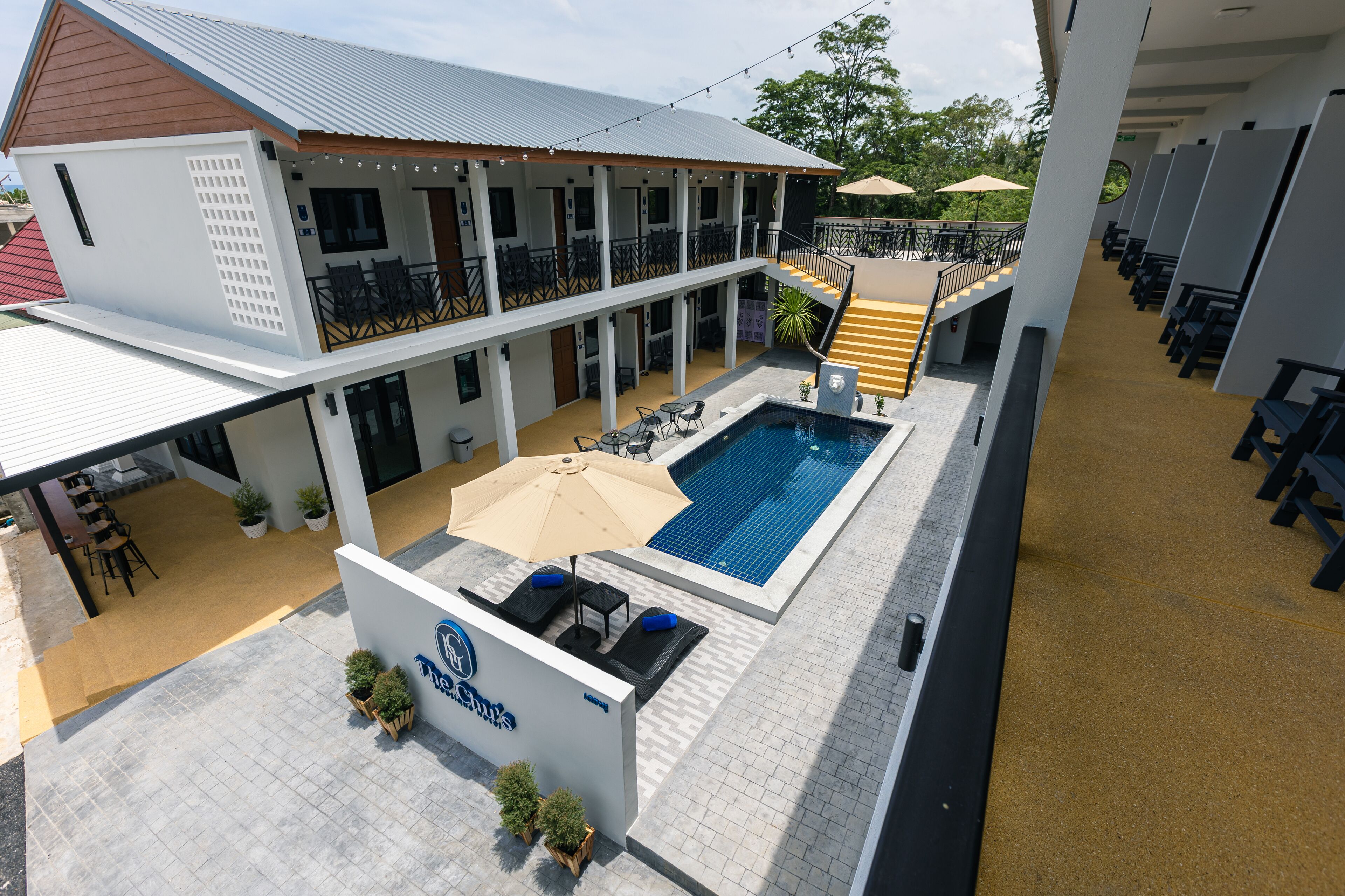 Un hotel con piscina, mobiliario exterior y un patio cubierto.
