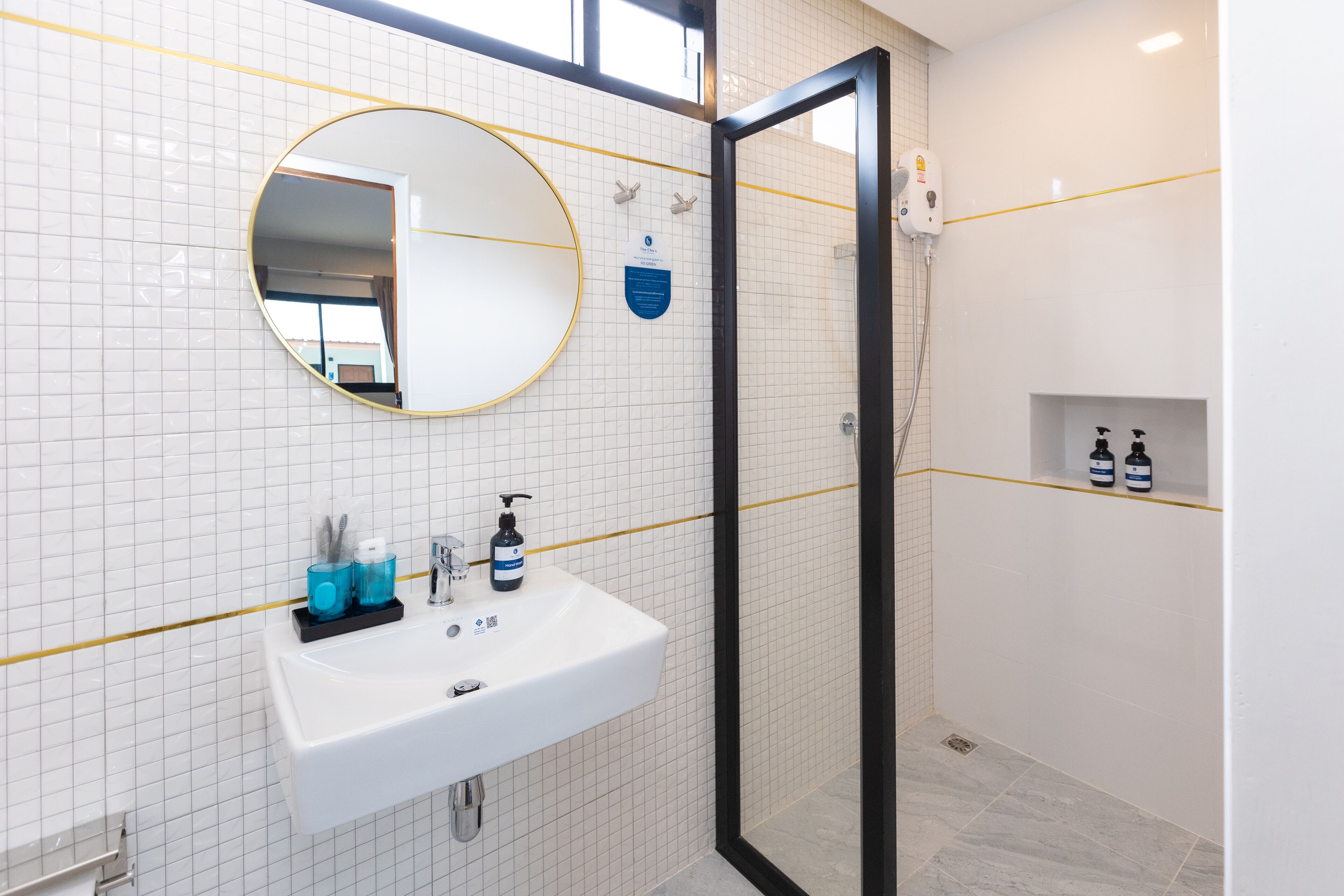 A bathroom with a white sink, a round mirror, and a glass-enclosed shower area.