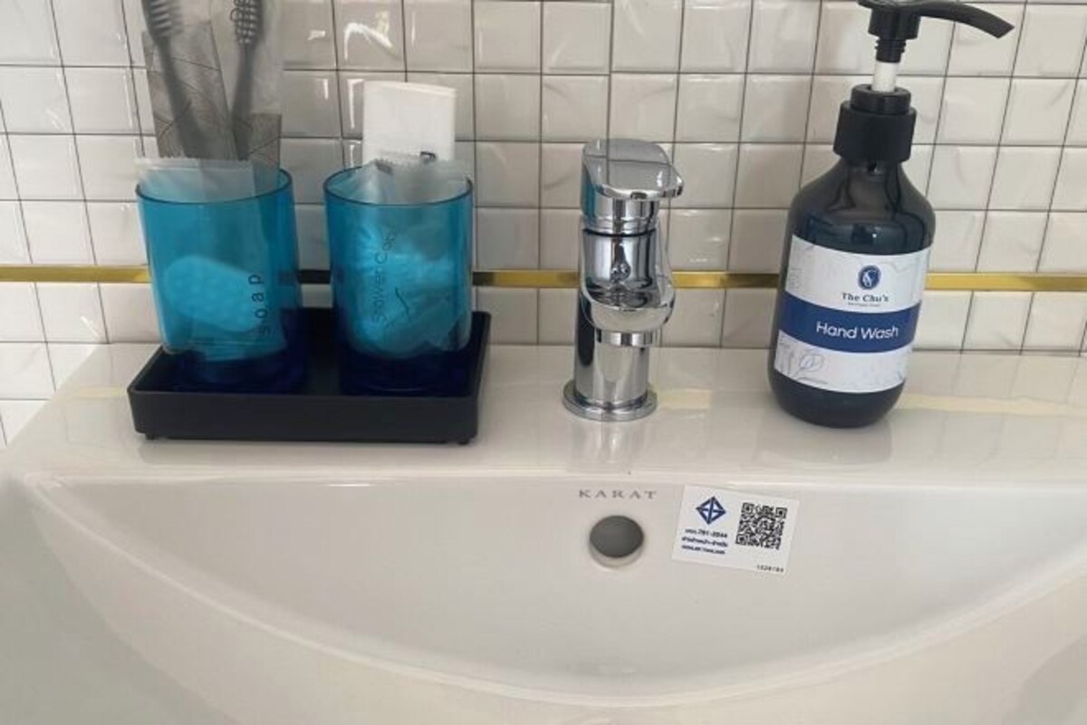 Un lavabo de salle de bain avec un distributeur de savon liquide, deux distributeurs de savon en verre bleu et un robinet.