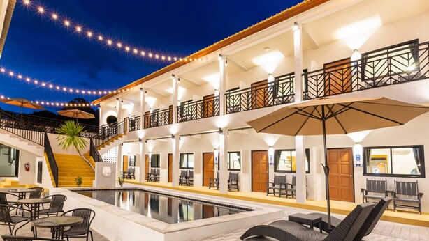 Un hotel con piscina, mobiliario exterior y una escalera que conduce al piso superior.