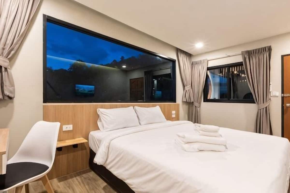 Una habitación de hotel moderna con una cama grande, un escritorio y vistas al exterior.