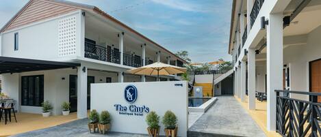 El hotel boutique Chu, con fachada blanca, zona de estar al aire libre y plantas en macetas.