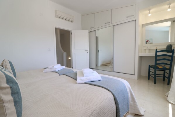 A bedroom with a bed, a wardrobe, a desk, and a chair.