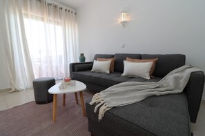 A modern living room with a grey sofa, a small round table, and a decorative lamp.
