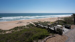 Ein Strand mit einer Holzterrasse und einer Sitzgelegenheit mit Blick auf den Ozean.