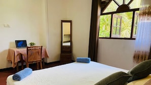A room with a bed, a desk with a laptop, a chair, a mirror, and a window with curtains. - Charming 2-bed Apartment in Weligama (Weligama)
