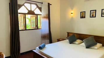 Habitación de hotel con cama, cortinas, ventana con vistas despejadas, mesita de noche y una obra de arte en la pared.