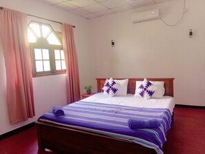 A hotel room with a bed, a window with curtains, an air conditioning unit, and a small potted plant. - Charming 2-bed Apartment in Weligama (Weligama)