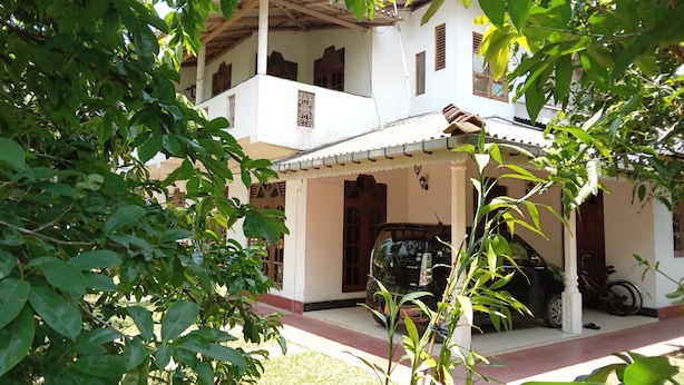 A two-story building with a covered porch and a car parked in front. - Charming 2-bed Apartment in Weligama (Weligama)
