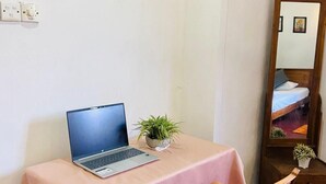 A small room with a laptop on a table, a chair, a potted plant, and a mirror reflecting a bed. - Charming 2-bed Apartment in Weligama (Weligama)