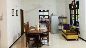 A dining area with a table set for four, a refrigerator, and a window with a view. - Charming 2-bed Apartment in Weligama (Weligama)