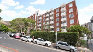 Un immeuble résidentiel à plusieurs étages, avec une façade en briques, des balcons et un ciel dégagé.