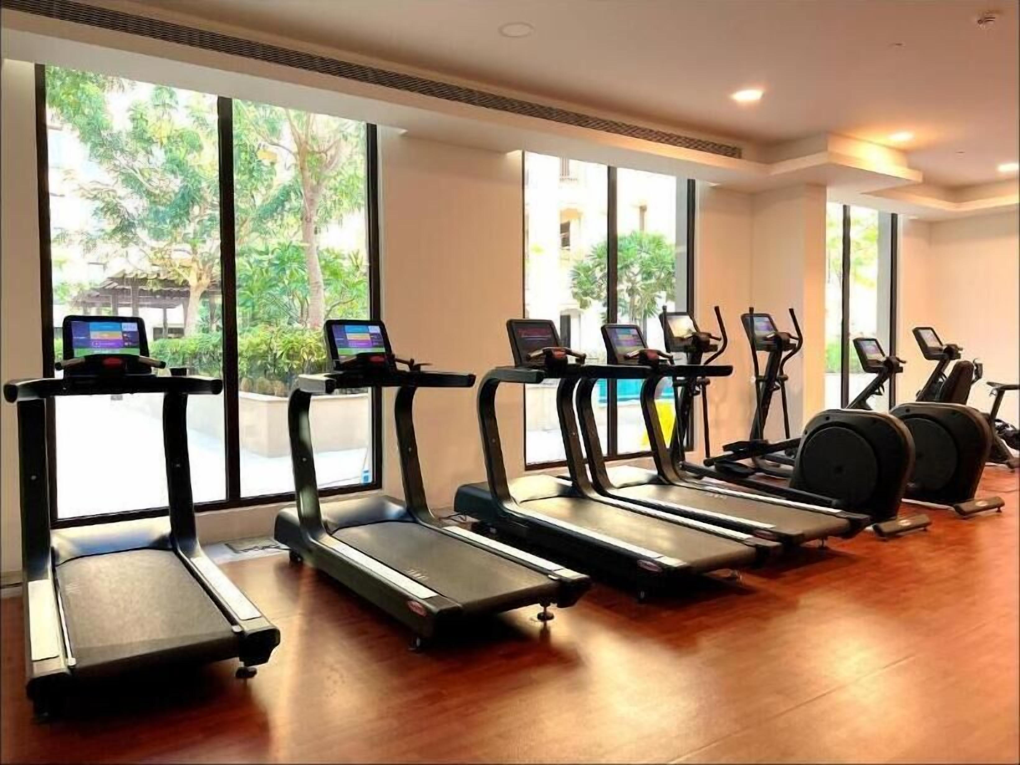 A gym with treadmills, elliptical machines, and a stationary bike, all equipped with screens.