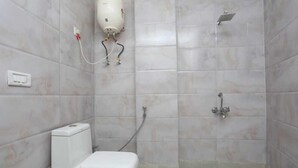 A small, tiled bathroom with a toilet, a shower, and a water heater. - Hotel The Mars (New Delhi)