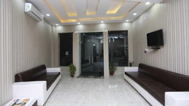 A reception area with a modern design, featuring a glass door entrance, a flat-screen TV mounted on the wall, and two seating areas with dark-colored sofas. - Hotel The Mars (New Delhi)