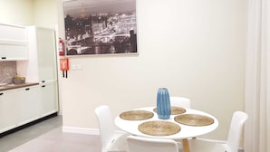 Ein Essbereich mit rundem Tisch, weißen Stühlen und einem Stadtbild als Wandbild.