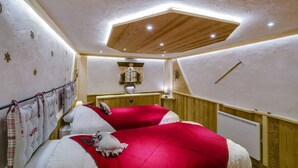 Un dormitorio con dos camas, paredes de madera, techo inclinado y una ventana pequeña.