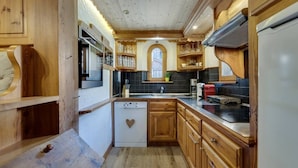 Una cocina compacta con muebles de madera, lavavajillas y encimera negra.