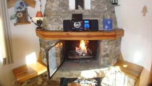 Una llar de pedra amb un panell de control digital, una petita estant a la part superior i una biga de fusta.