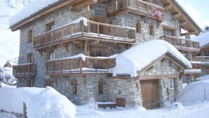 Un edifici de pedra de diversos pisos amb balcons de fusta i un teulat cobert de neu.