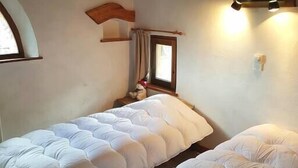 A room with two beds, wooden beams, a window, and a nightstand with a lamp. - N5 Chalet apartment4****South West 10/11 guests/Slopes foot (Val-d'Isère)