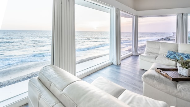 A modern living room with a large window overlooking a beach.