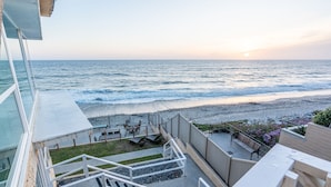 A balcony with a view of the ocean and a beach.
