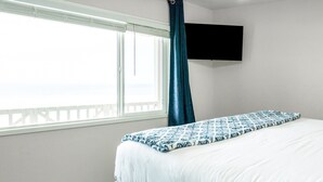 A hotel room with a bed, a TV mounted on the wall, and a window with a curtain. - Ideal Location on the Sand - Beach Views and Access (Carlsbad)