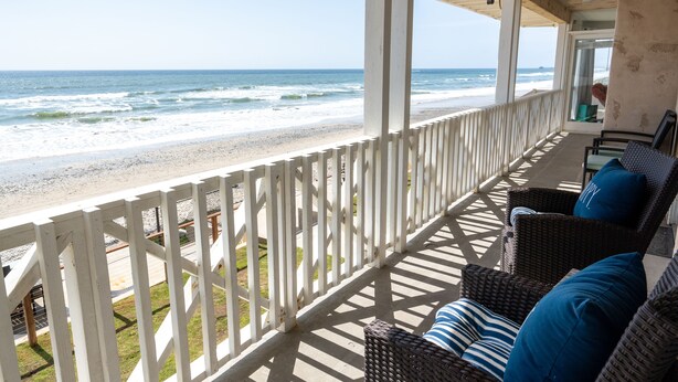 A covered balcony with wicker furniture and a view of the beach. - Ideal Location on the Sand - Beach Views and Access (Carlsbad)