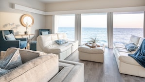Ein geräumiges Wohnzimmer mit großem Fenster mit Meerblick, ausgestattet mit zwei Sofas und einem Couchtisch.