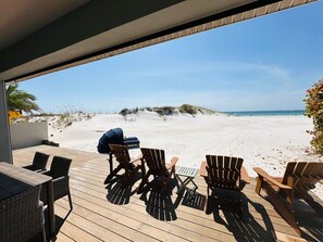 A wooden deck with outdoor seating and a view of a sandy beach and ocean. - St Pete Beach Don Cesar Pool On The Sand (St Pete Beach)