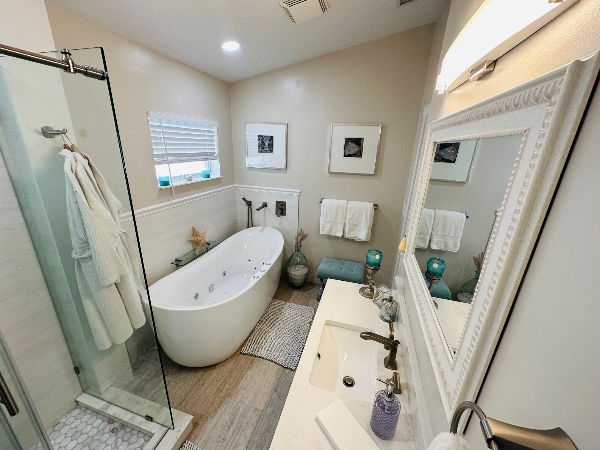 Un baño moderno con una bañera independiente, un espejo grande y un tocador con lavamanos.