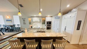 A kitchen with a central island, white cabinets, and pendant lighting.