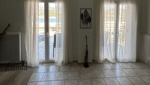 Ein geräumiges Zimmer mit großen Fenstern, einem Heizkörper und einer Gitarre.