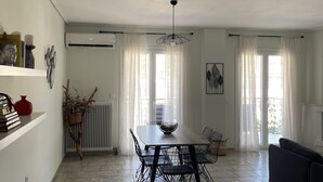 Ein großzügiger Wohnbereich mit Esstisch, schwarzen Stuhlgestellen, einer schwarzen Couch und einem Kamin.