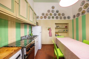 Een keuken met gestreepte groene en witte wanden, een houten aanrecht, een fornuis, een spoelbak en een eettafel met een strepen tafelkleed.