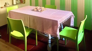En matplats med ett bord dukat för fyra personer, gröna stolar, en röd hänglampa och en vägg dekorerad med gamla kapsyler från flaskor.